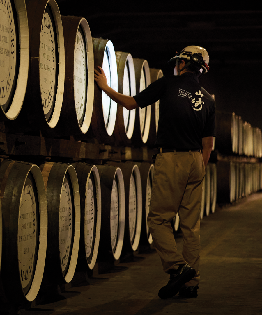 Worker observing whisky barrels